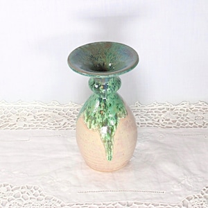 May include: A ceramic vase with a wide, flared rim and a bulbous body. The upper portion and rim feature a glossy, mottled green glaze that drips down onto the lower section, which is a matte, speckled light beige or cream-colored clay finish.