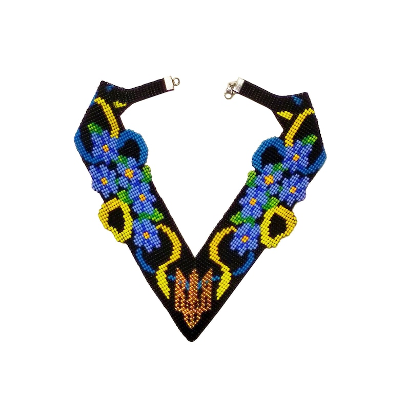 Puede incluir: Un collar de cuentas negras con un dise&ntilde;o en forma de V. El collar presenta flores azules y amarillas con hojas verdes.