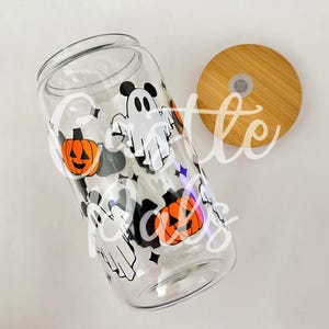 Può includere: Un barattolo di vetro trasparente con un coperchio in bambù. Il barattolo è decorato con un tema di Halloween con fantasmi e zucche.