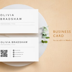 May include: A white business card with the name Olivia Bradshaw and a professional title. The card also includes a phone number, email address, street address, and social media handle. The card is on a white plate with a sprig of eucalyptus.