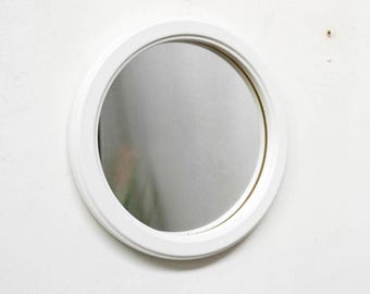 May include: A white round mirror with a simple white frame.