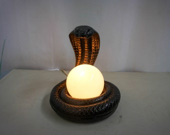 Black plaster table lamp, cobra holding a glass ball