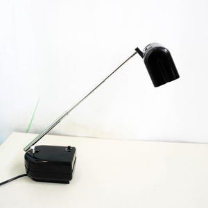 May include: A black desk lamp with a long, adjustable arm and a black shade. The lamp has a chrome base and a black cord.