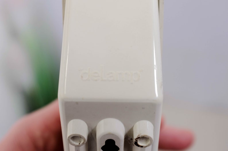 K&ouml;nnte beinhalten: Nahaufnahme einer wei&szlig;en Steckdose mit dem aufgedruckten Wort "delamp". Die Steckdose hat drei Stifte.