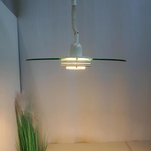May include: A white ceiling light fixture with a glass shade and a flexible arm. The light is on and illuminating the room.