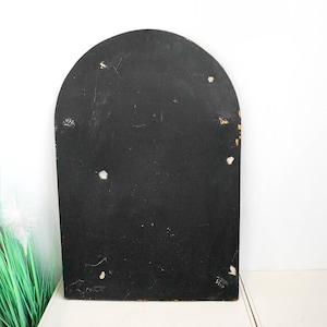 May include: A black arched wooden frame with a smooth surface. The frame has a few small white marks on the surface.