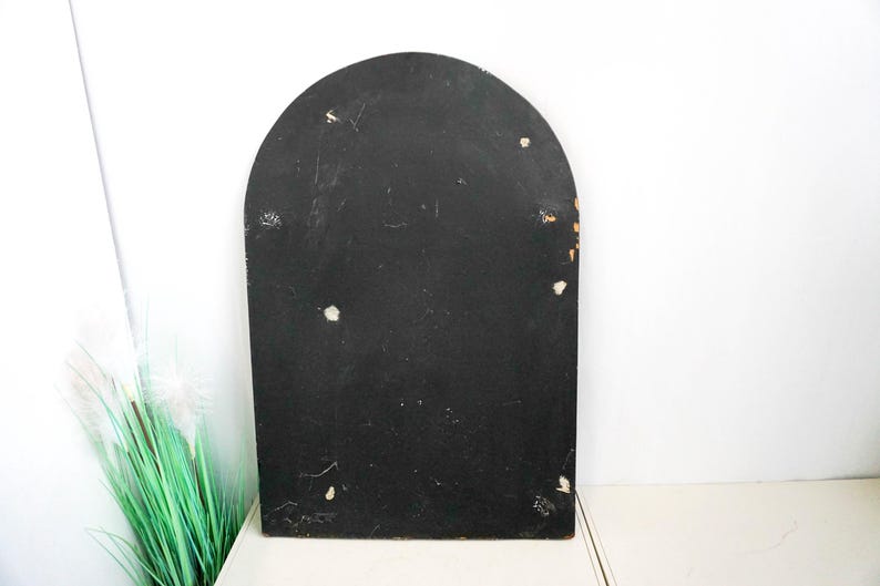 May include: A black arched wooden frame with a smooth surface. The frame has a few small white marks on the surface.