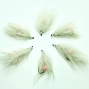 May include: Six white and pink fly fishing lures with a white feather body and a pink bead head.