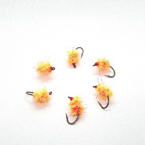 May include: Six yellow and orange fly fishing lures with black hooks.