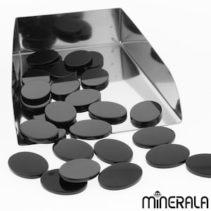 Peut inclure: Un plateau de pierres précieuses ovales noires. Le plateau est en métal et a une surface brillante. Les pierres précieuses sont lisses et polies.