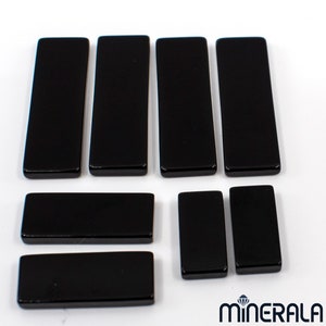 May include: A set of ten black rectangular gemstone cabochons. The cabochons are polished and smooth.