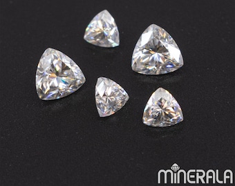May include: Five clear, triangular, faceted gemstones on a black background. The gemstones are all different sizes and have a brilliant sparkle.