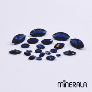 Peut inclure: Assortiment de pierres précieuses bleues de forme marquise de différentes tailles. Les pierres précieuses sont facettées et ont une couleur bleu foncé.