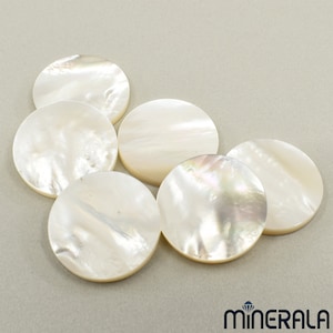 May include: Six white mother-of-pearl round cabochons with iridescent shimmer. The cabochons are smooth and polished.