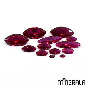 Puede incluir: Un conjunto de gemas facetadas con corte marquesa de varios tamaños. Las gemas son de un color rojo intenso, con un alto grado de claridad y brillo. Las gemas están dispuestas sobre un fondo blanco, con la marca "MINERALA" en la esquina inferior derecha.
