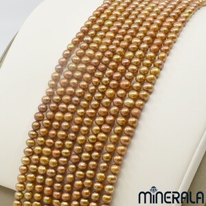 May include: A strand of golden brown freshwater pearls. The pearls are round and smooth, with a slight iridescent sheen. The strand is approximately 18 inches long.