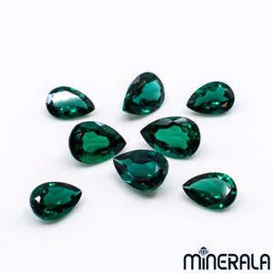 Puede incluir: Ocho piedras preciosas verdes en forma de pera sobre un fondo blanco.