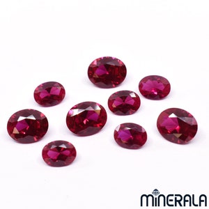 Pode incluir: Uma coleção de nove gemas ovaladas de cor vermelha. As gemas são facetadas e têm um alto polimento.