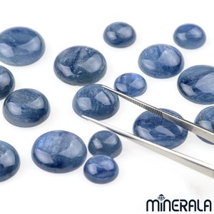 Könnte beinhalten: Eine Sammlung runder, blauer Edelstein-Cabochons in verschiedenen Größen, einige mit einer Pinzette auf weißem Hintergrund gehalten.