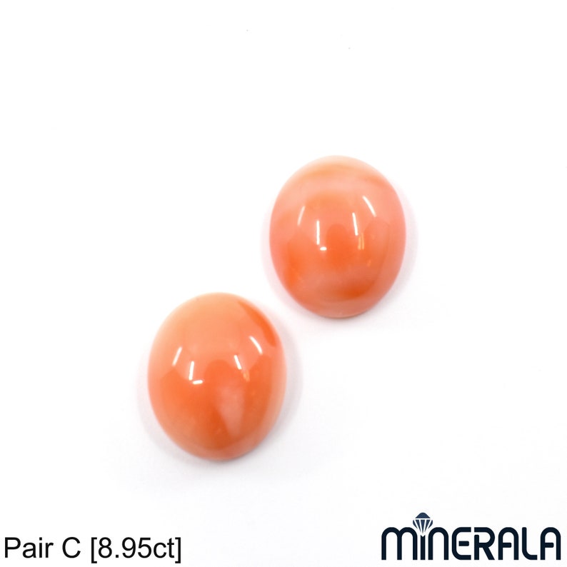 May include: Pair of round, smooth, coral cabochons. The cabochons are a light orange color with a slight pink hue. The cabochons are approximately 8.95 carats.