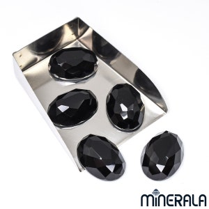 Peut inclure: Cinq pierres pr&eacute;cieuses noires de forme ovale dans un plateau en m&eacute;tal. Les pierres pr&eacute;cieuses sont facett&eacute;es et ont une finition brillante.