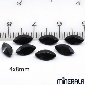 以下が含まれることがあります： 白い背景に、約4x8mmの黒いマーキス型の宝石が7つ並んでいます。宝石はファセットカットされており、光を反射して光沢のある表面を見せています。画像にはスケール用の定規と「4x8mm」の文字が含まれています。