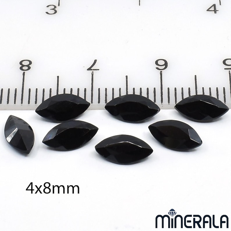 以下が含まれることがあります： 白い背景に、約4x8mmの黒いマーキス型の宝石が7つ並んでいます。宝石はファセットカットされており、光を反射して光沢のある表面を見せています。画像にはスケール用の定規と「4x8mm」の文字が含まれています。