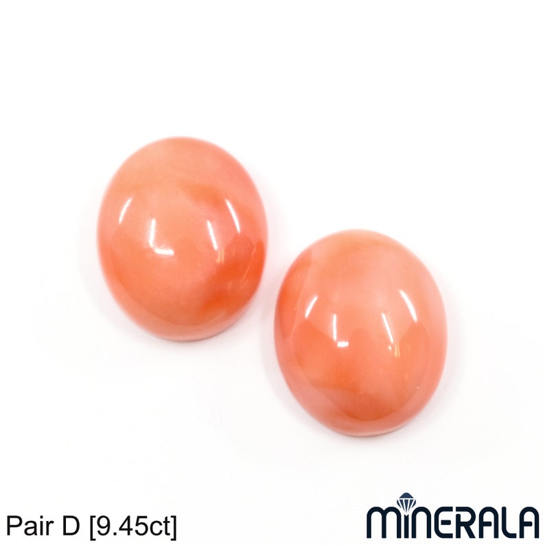 May include: Pair of round, smooth, coral cabochons. The cabochons are a light peach color. Pair D [9.45ct]