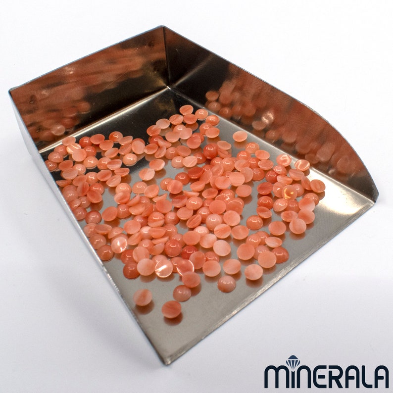 Pu&ograve; includere: Una paletta di metallo piena di una grande quantit&agrave; di piccoli cabochon rotondi di colore pesca.
