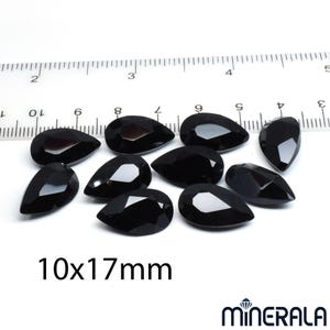 Puede incluir: Diez gemas negras en forma de l&aacute;grima, de aproximadamente 10 x 17 mm cada una, se muestran sobre una superficie blanca junto a una regla. El texto "10x17mm" es visible. El logotipo de Minerala est&aacute; en la esquina inferior derecha.