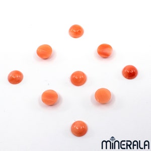 Pu&ograve; includere: Nove cabochon rotondi in corallo liscio, in varie tonalit&agrave; di arancio e rosa. I cabochon sono disposti in modo sparso su uno sfondo bianco.