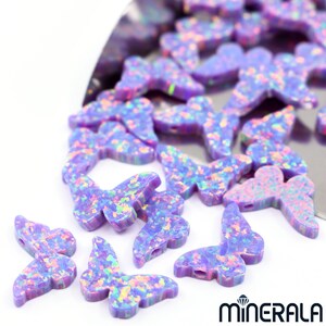 Puede incluir: Un conjunto de cuentas de &oacute;palo en forma de mariposa de color p&uacute;rpura iridiscente. Las cuentas tienen un acabado moteado y brillante y son perfectas para la elaboraci&oacute;n de joyas.