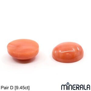 May include: Pair of round, smooth, coral cabochons, each measuring approximately 9.45 carats. The coral is a vibrant orange-red color.