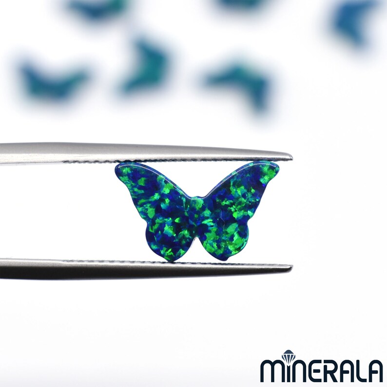 Puede incluir: Una piedra preciosa de &oacute;palo en forma de mariposa, de color verde y azul, sostenida por unas pinzas. El &oacute;palo tiene un acabado brillante e iridiscente.