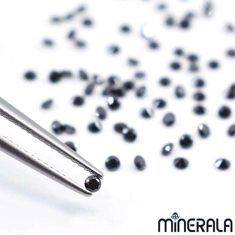 May include: A close-up of a black diamond held by tweezers, surrounded by a scattering of loose black diamonds on a white surface. The image is labelled "MINERALA".