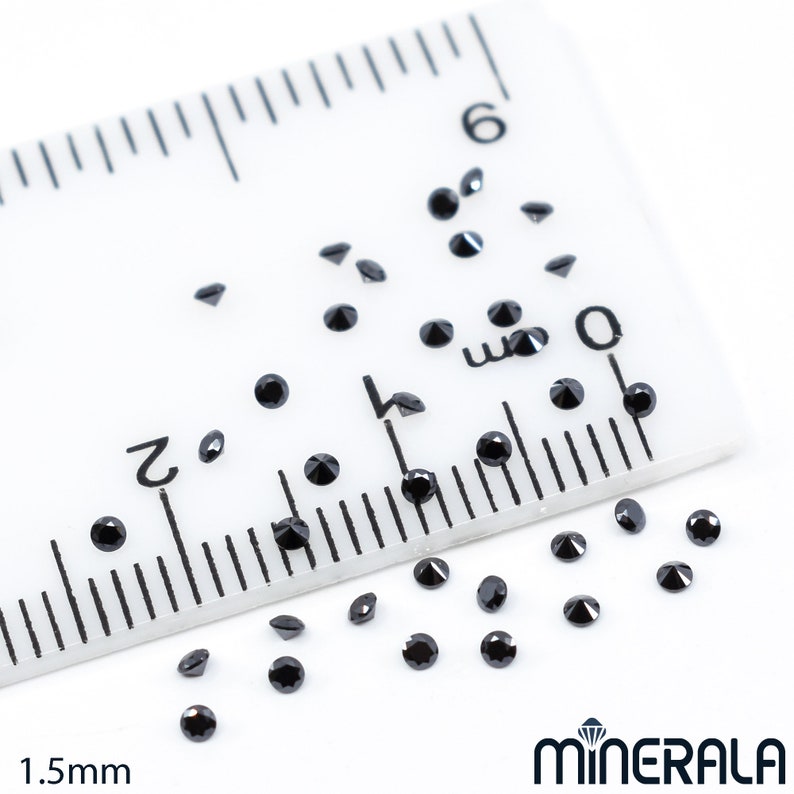May include: A ruler with black diamond-shaped gemstones scattered on a white surface. The ruler is marked in millimetres and shows a measurement of 1.5mm.