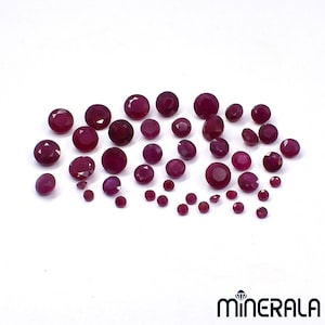 Pode incluir: Uma coleção de numerosos rubis redondos, facetados e vermelho-escuros de vários tamanhos dispostos num grupo solto. Cada pedra preciosa apresenta um corte brilhante com múltiplas facetas que refletem a luz, criando um brilho.