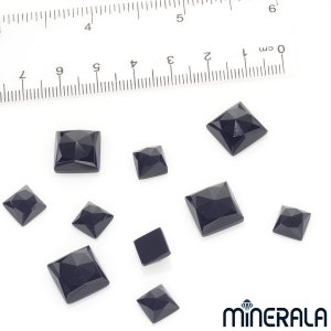 Puede incluir: Colecci&oacute;n de gemas negras facetadas, de corte cuadrado y de varios tama&ntilde;os. Una regla con marcas de cent&iacute;metros se encuentra en el fondo. Las gemas est&aacute;n dispuestas sobre una superficie blanca. El logotipo de Minerala est&aacute; en la esquina inferior derecha.
