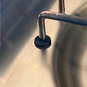 Può includere: Primo piano di un lavello in acciaio inossidabile con un tappo di gomma nero nello scarico.