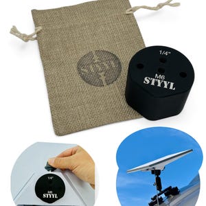 Op de afbeelding: Zwarte 1/4 inch M6 antennebevestiging met drie gaten. De bevestiging is gemaakt van metaal en heeft het woord "STYYL" erop gegraveerd. De bevestiging wordt geleverd met een kleine jute zak.