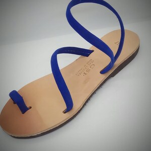 Puede incluir: Sandalias de cuero azul con un bucle para el dedo del pie y una sola correa que se envuelve alrededor del tobillo. Las sandalias est&aacute;n hechas en Grecia y est&aacute;n etiquetadas como "GST" y "Genuine Leather Made in Greece".