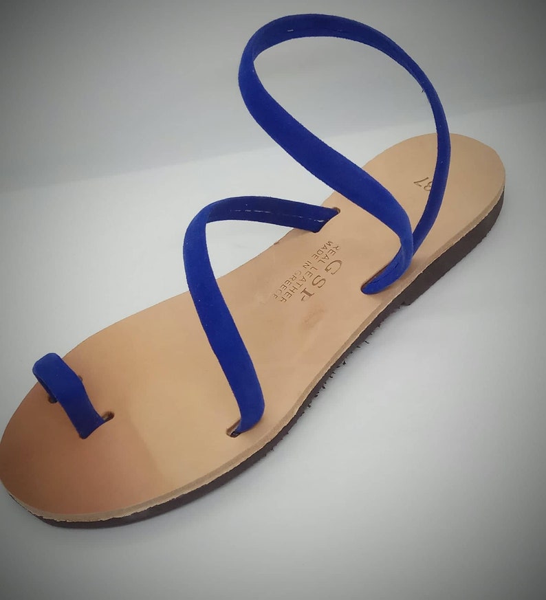 Puede incluir: Sandalias de cuero azul con un bucle para el dedo del pie y una sola correa que se envuelve alrededor del tobillo. Las sandalias est&aacute;n hechas en Grecia y est&aacute;n etiquetadas como "GST" y "Genuine Leather Made in Greece".