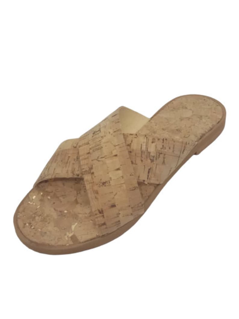May include: Cork sandals with a criss-cross strap design. The sandals are a light brown color and have a flat sole.