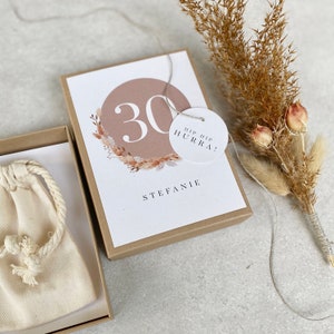 Könnte beinhalten: Eine braune Box mit einer weißen Karte darin. Die Karte hat einen rosa Kreis mit der Zahl 30 in weißer Schrift. Die Karte hat auch einen weißen Kreis mit dem Text "Hip Hip Hurra!" und dem Namen "Stefanie".