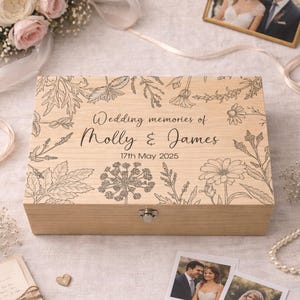 May include: A wooden memory box with floral engravings and the text "Wedding memories of Molly & James 17th May 2025." The box is surrounded by wedding-themed items, including photos, rings, and flowers.
