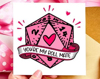 May include: A pink and white card with a pink heart and a pink and black dice with the text "You're my roll mate".