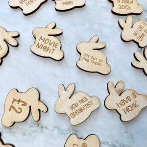 May include: Wooden bunny-shaped tokens with various activities and rewards written on them, such as "Movie Night", "Craft Time", "Get Out of One Chore", "You Pick Breakfast", "Have a Picnic", "Go on a Bike Ride", "£5", and "£2".