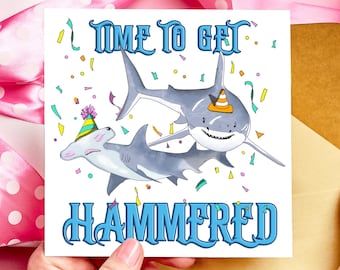 May include: A white greeting card with a cartoon illustration of two sharks, one with a party hat. The card has the text "TIME TO GET HAMMERED" in blue. Confetti in yellow, green, and pink surrounds the sharks.