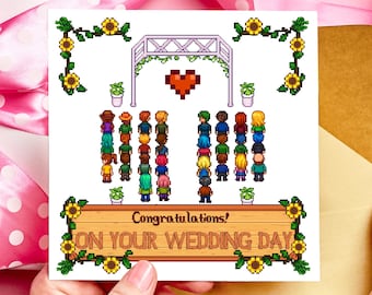 May include: A square greeting card with a pixelated wedding scene. The card features a wooden sign that reads "Congratulations! ON YOUR WEDDING DAY." The design includes a heart, an archway, sunflowers, and pixelated figures representing wedding guests.