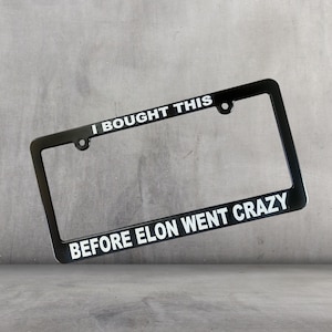 May include: Black license plate frame with white text that reads "I bought this before Elon went crazy".
